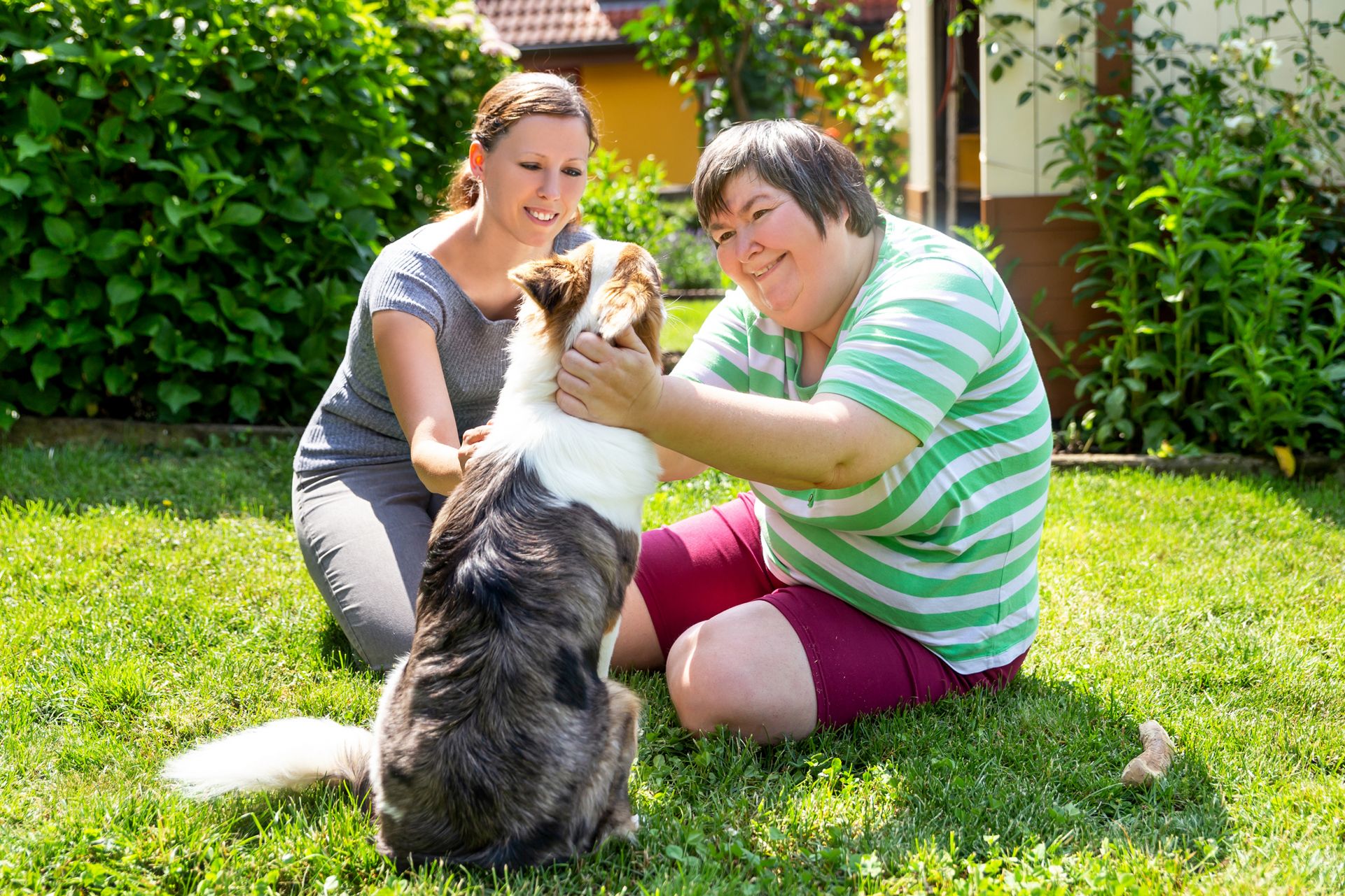 idd support person working with woman with developmental disabilities and petting a dog